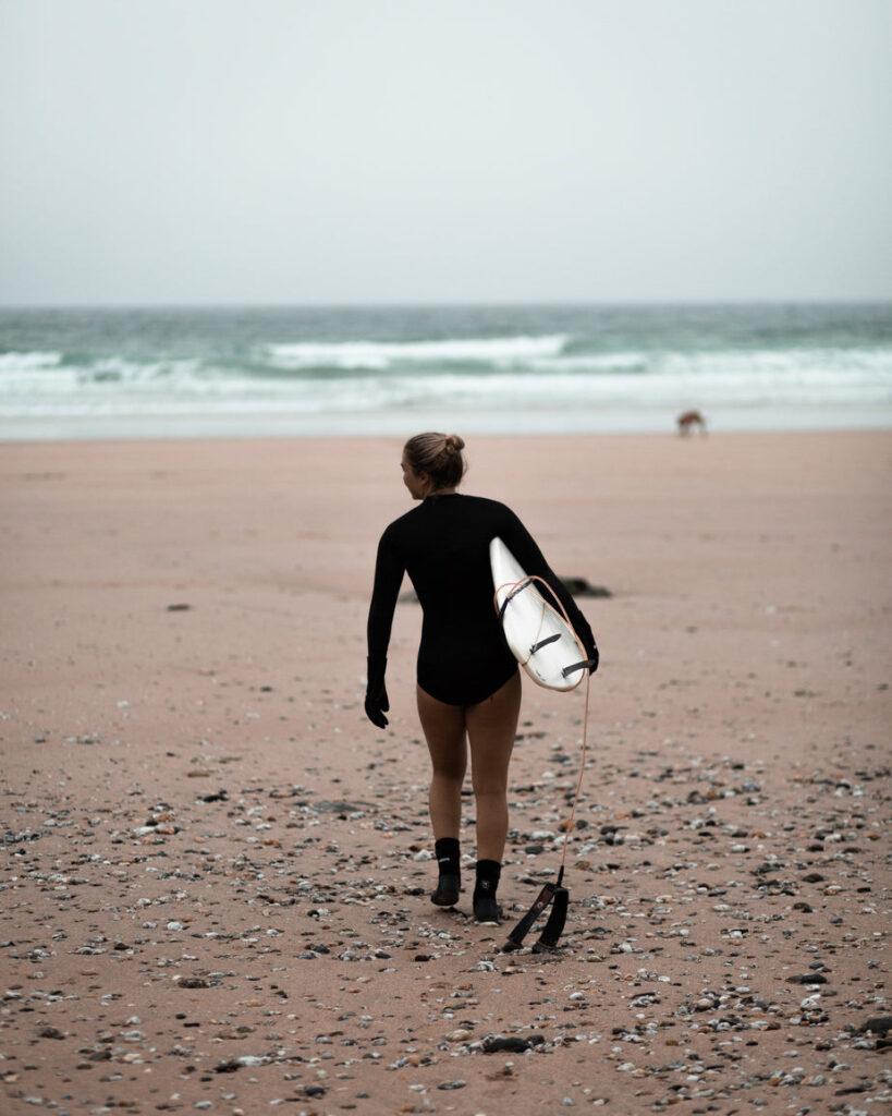 Women carries surfboard on the beach