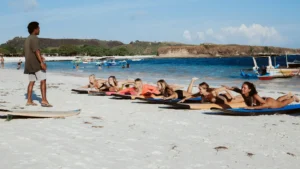 Surfwell instructors give lessons on standing on a surfboard at the edge of Kuta Lombok beach