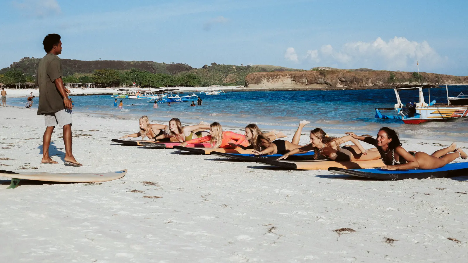 Surfwell instructors give lessons on standing on a surfboard at the edge of Kuta Lombok beach