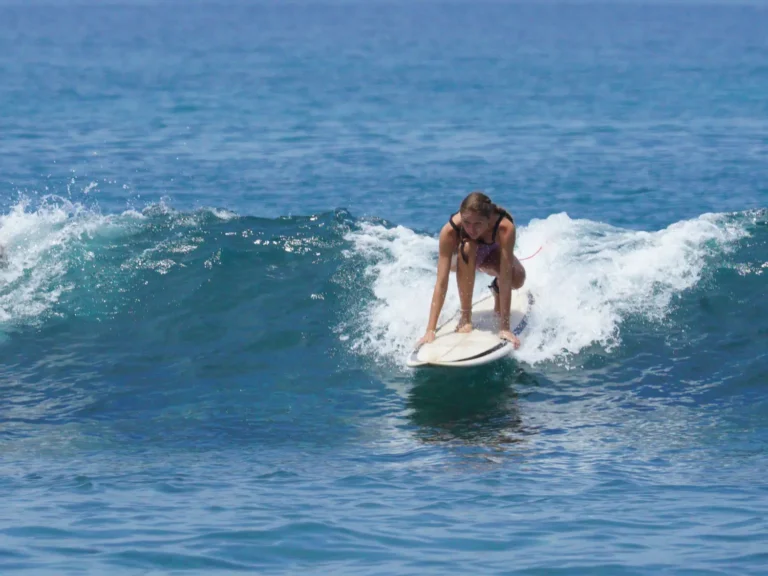 Girl attempting to stand on a board during surf lessons in Kuta Beach Lombok