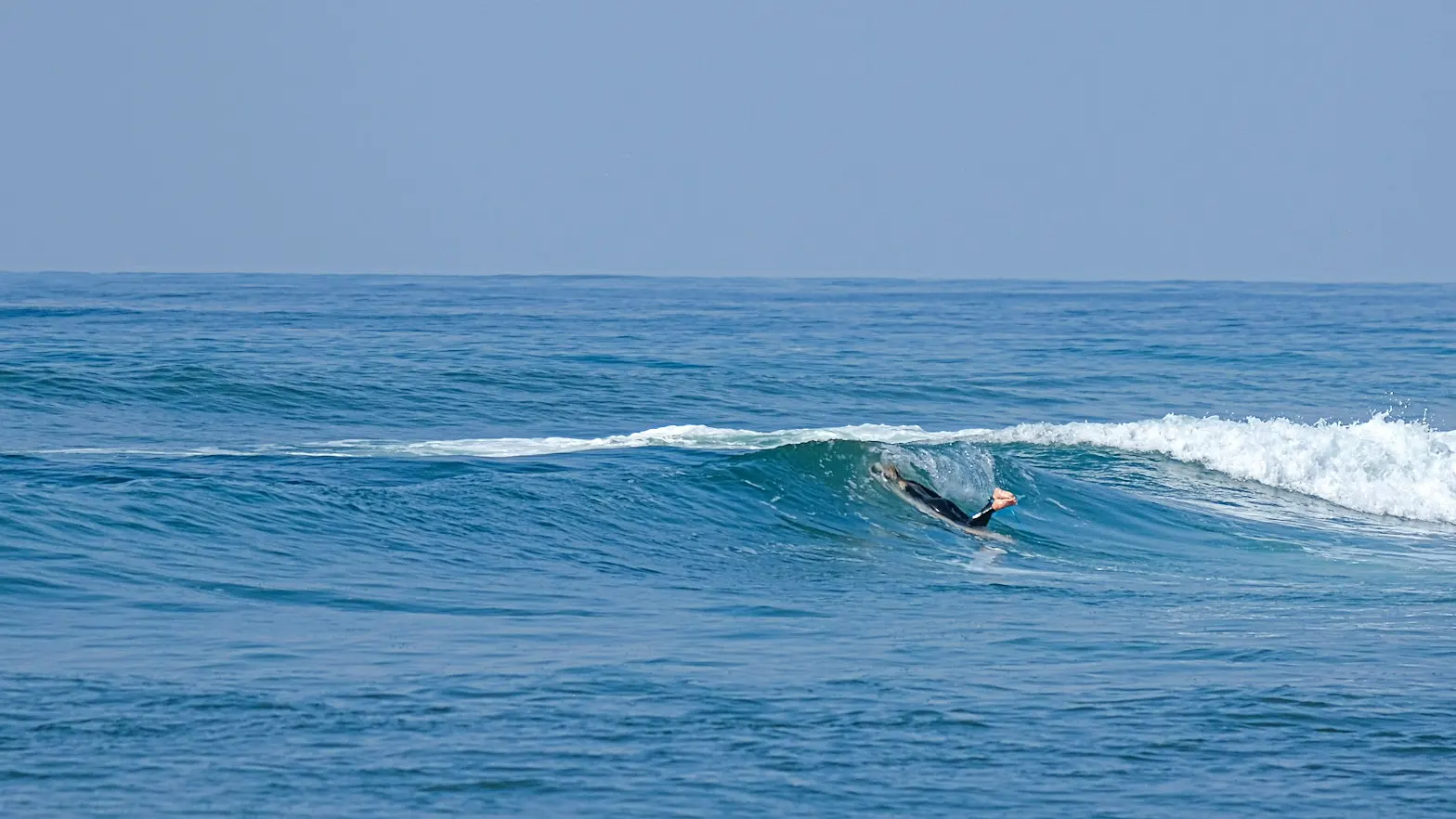 Surfers checking the Tanjung Aan surf forecast with waves breaking at Tanjung Aan Beach, Lombok