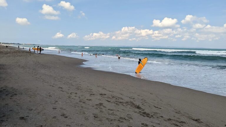Surfing atmosphere in Canggu Bali with surfers riding waves at Batu Bolong Beach