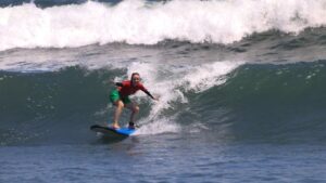 Student practicing a stand up on a surfboard during a SurfWell surfing lesson in Canggu