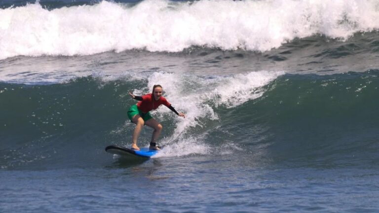 Student practicing a stand up on a surfboard during a SurfWell surfing lesson in Canggu