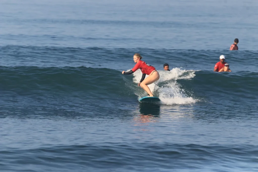 A beginner surfer riding their first wave with perfect balance, guided by a licensed instructor from Surfwell Bali.